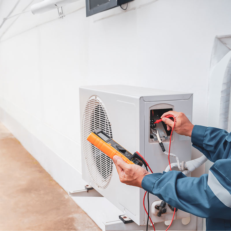 a technician using a meter reader to test a HVAC unit