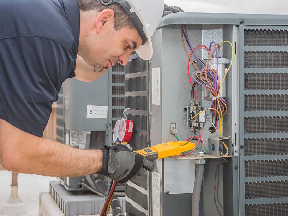 professional hvac technician measuring amperage on an air conditioner unit