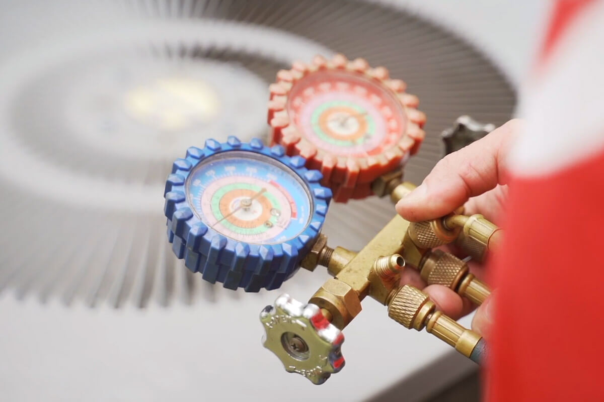 close up of a technician using a gauge to measure air conditioning refrigerant